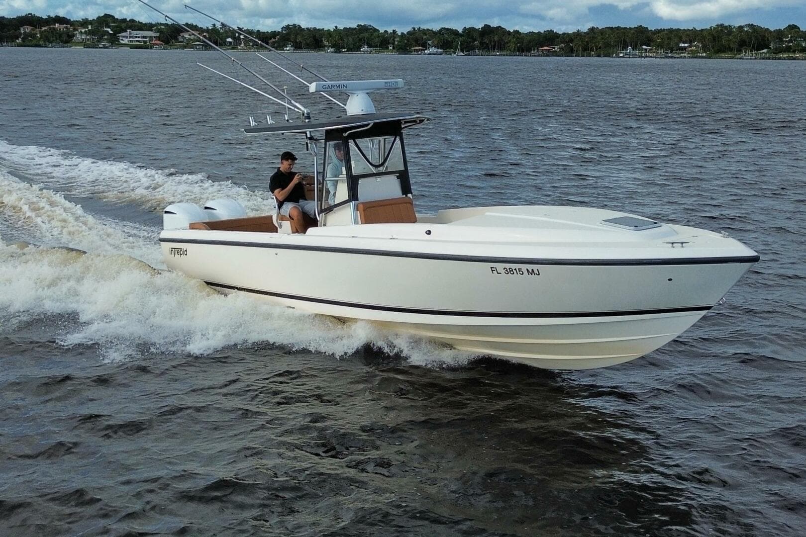 2004 Intrepid 32 Cuddy boat cruising on water with person at helm.