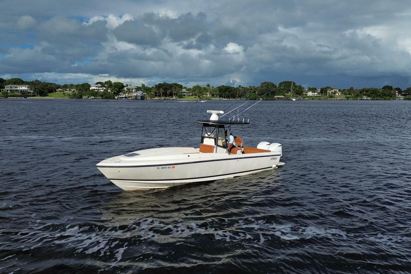 2004 Intrepid 32 Cuddy boat cruising on a scenic waterway under cloudy skies.