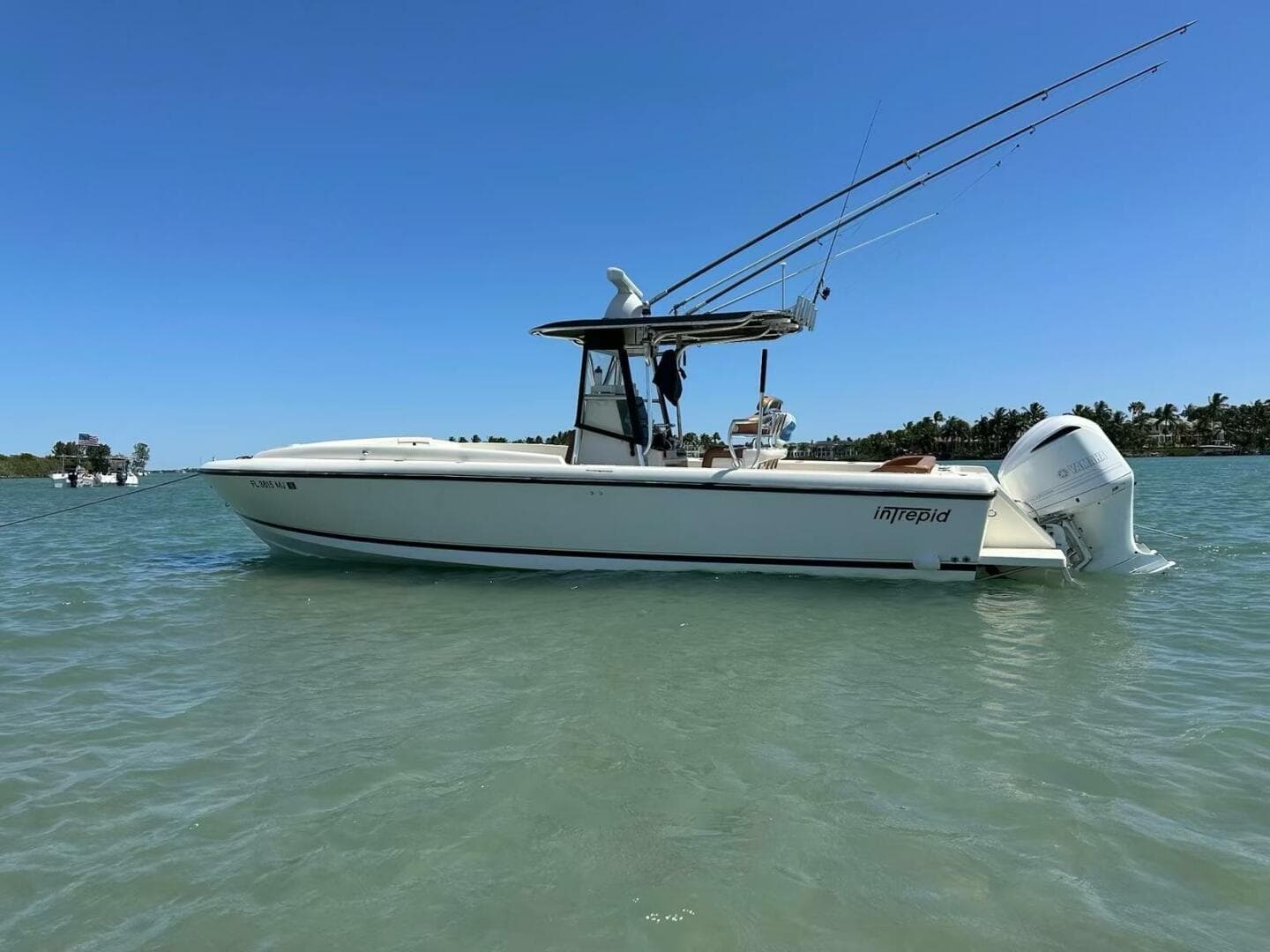 2004 Intrepid 32 Cuddy boat on water, clear sky, fishing rods visible.