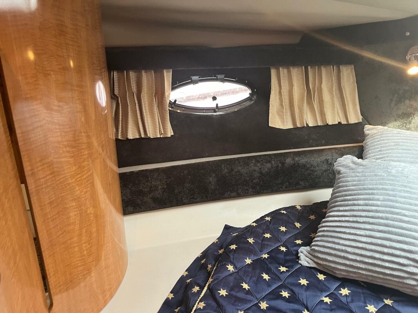 2003 Regal Commodore 3860 cabin interior with bed, porthole, and wooden cabinetry.