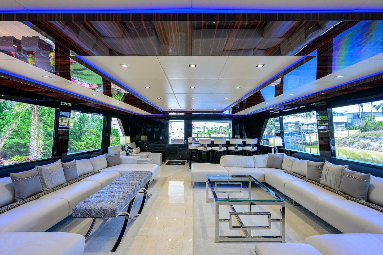 Luxurious interior of 1997 Broward 108 Raised Pilothouse yacht with modern seating and glass tables.