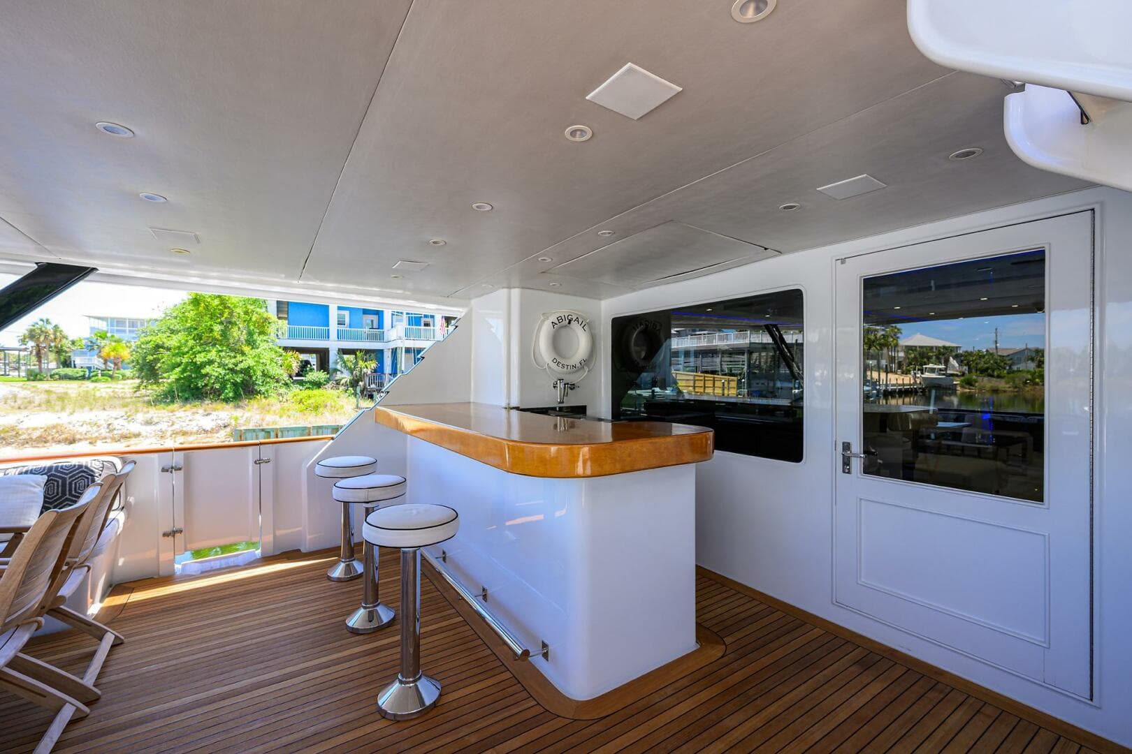 Outdoor bar area on 1997 Broward 108 Raised Pilothouse yacht with stools and wooden deck.