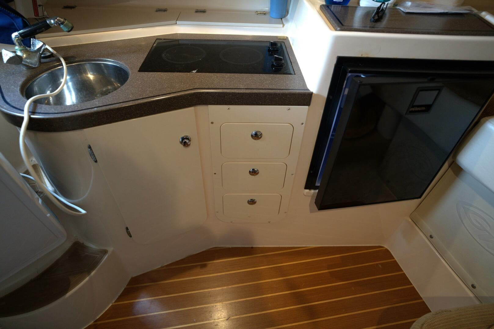 2007 Grady-White Express 330 boat kitchen with sink, stove, and mini fridge.