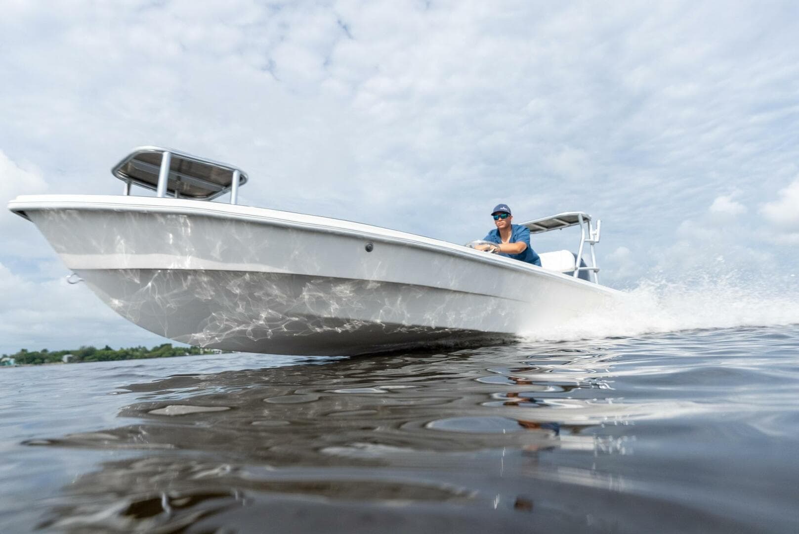 2025 BlueZones Boatworks 16' Flats boat cruising on water under cloudy sky.
