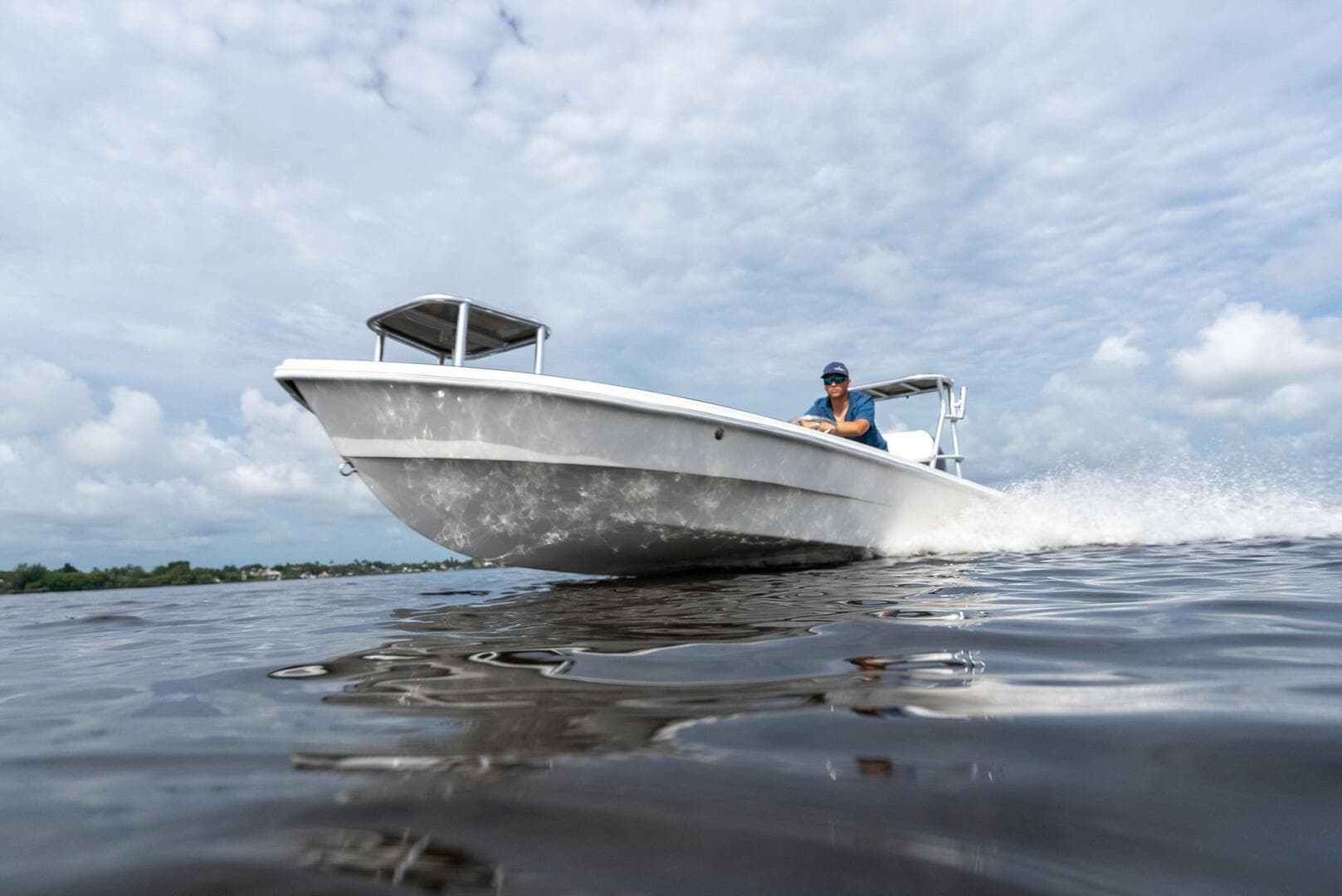 2025 BlueZones Boatworks 16' Flats boat cruising on open water under cloudy skies.