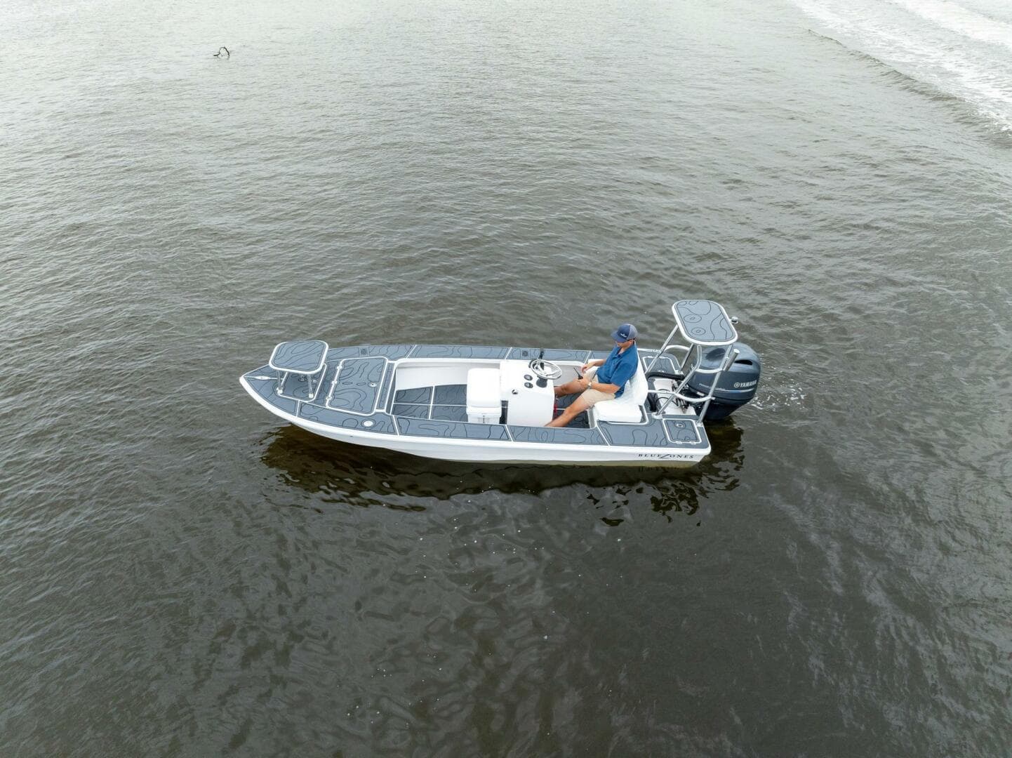 2025 BlueZones Boatworks 16' Flats boat on calm water, aerial view.