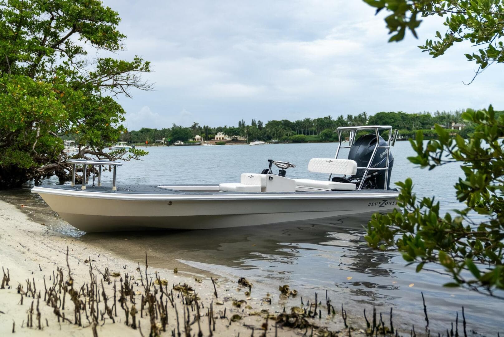 2025 BlueZones Boatworks 16' Flats boat docked by a serene shoreline.