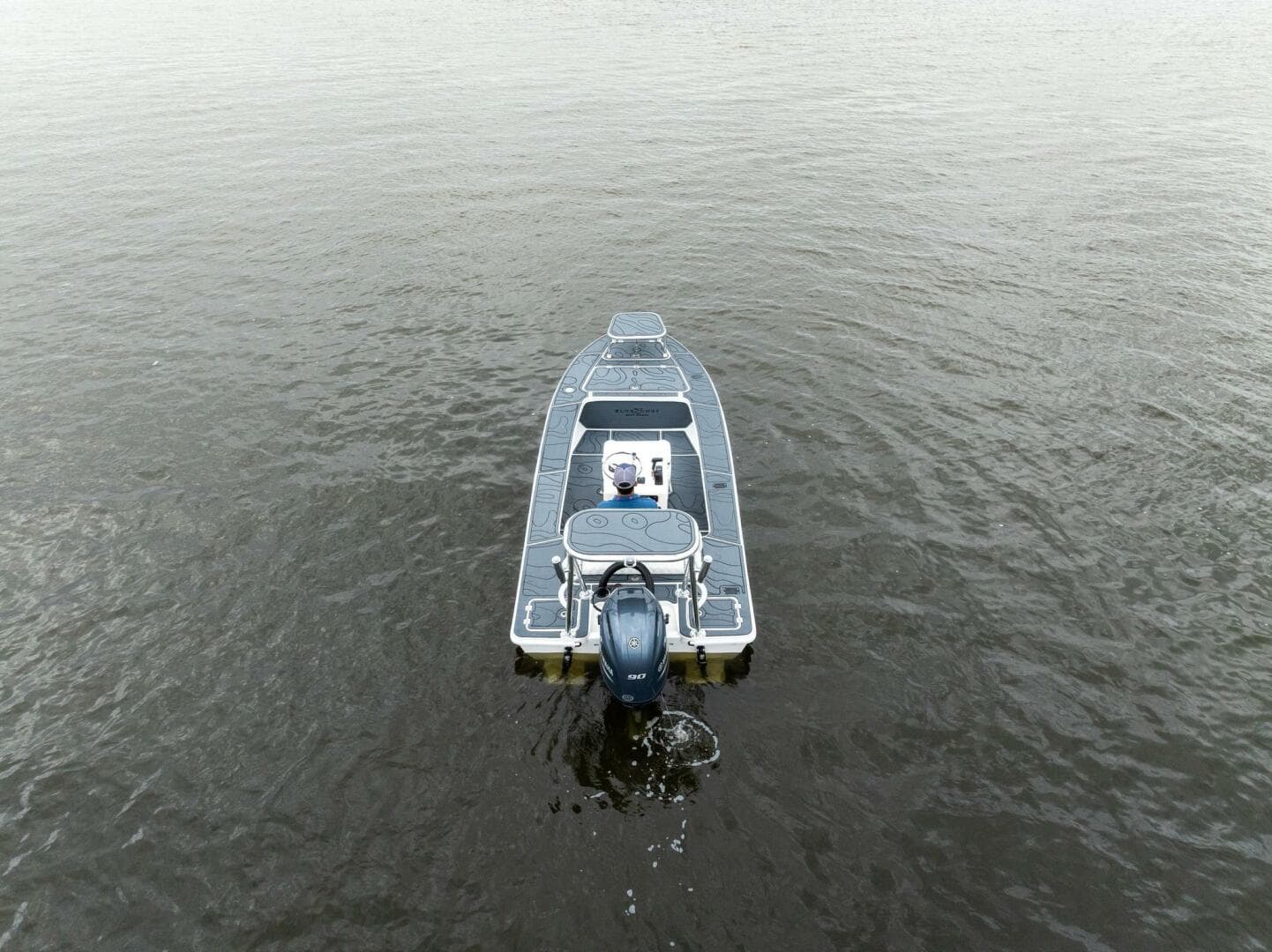 2025 BlueZones Boatworks 16' Flats boat on calm water, aerial view.