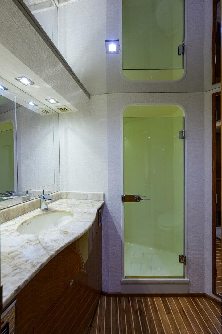 2004 Viking 65 Enclosed Bridge yacht bathroom with marble countertop and glass shower doors.