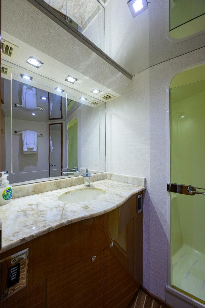 Luxurious bathroom on 2004 Viking 65 Enclosed Bridge yacht with marble countertop and shower.