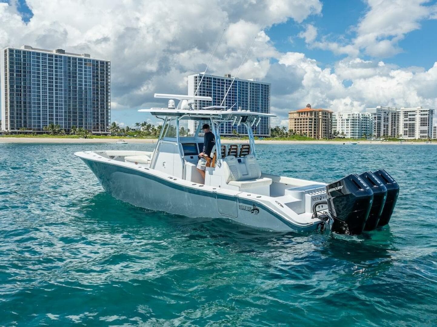 2025 Billfish 39 Center Console boat with tower on clear blue water, city skyline backdrop.