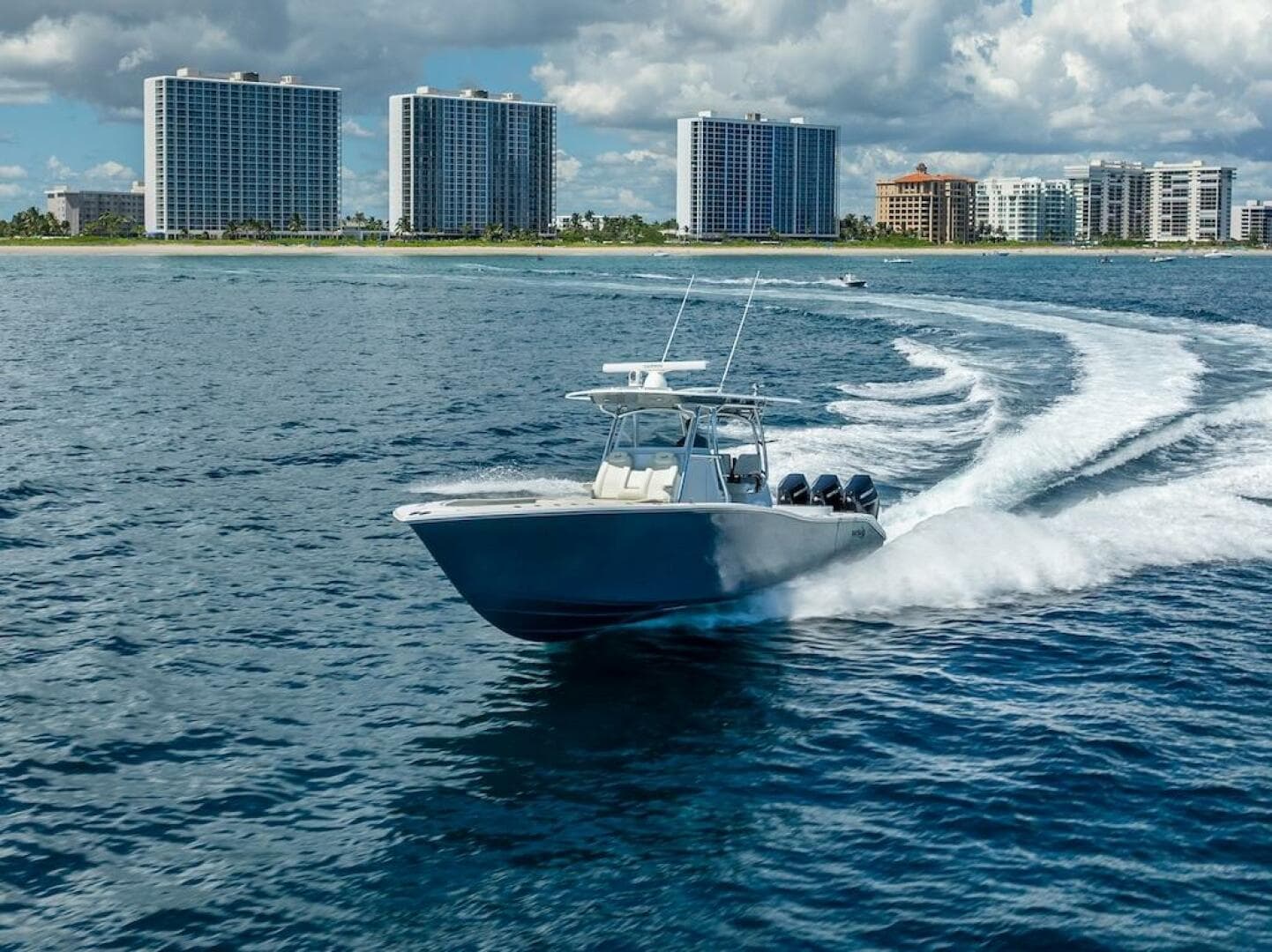 2025 Billfish 39 Center Console boat cruising near coastal skyscrapers.