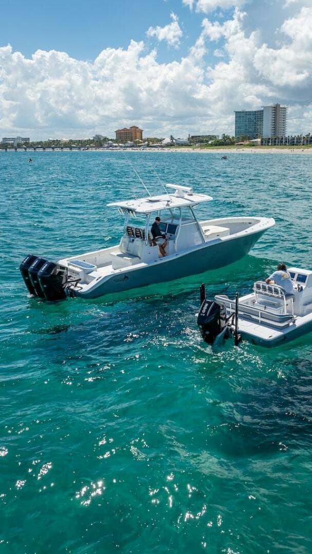 2025 Billfish 39 Center Console boat on clear blue water near a beach.