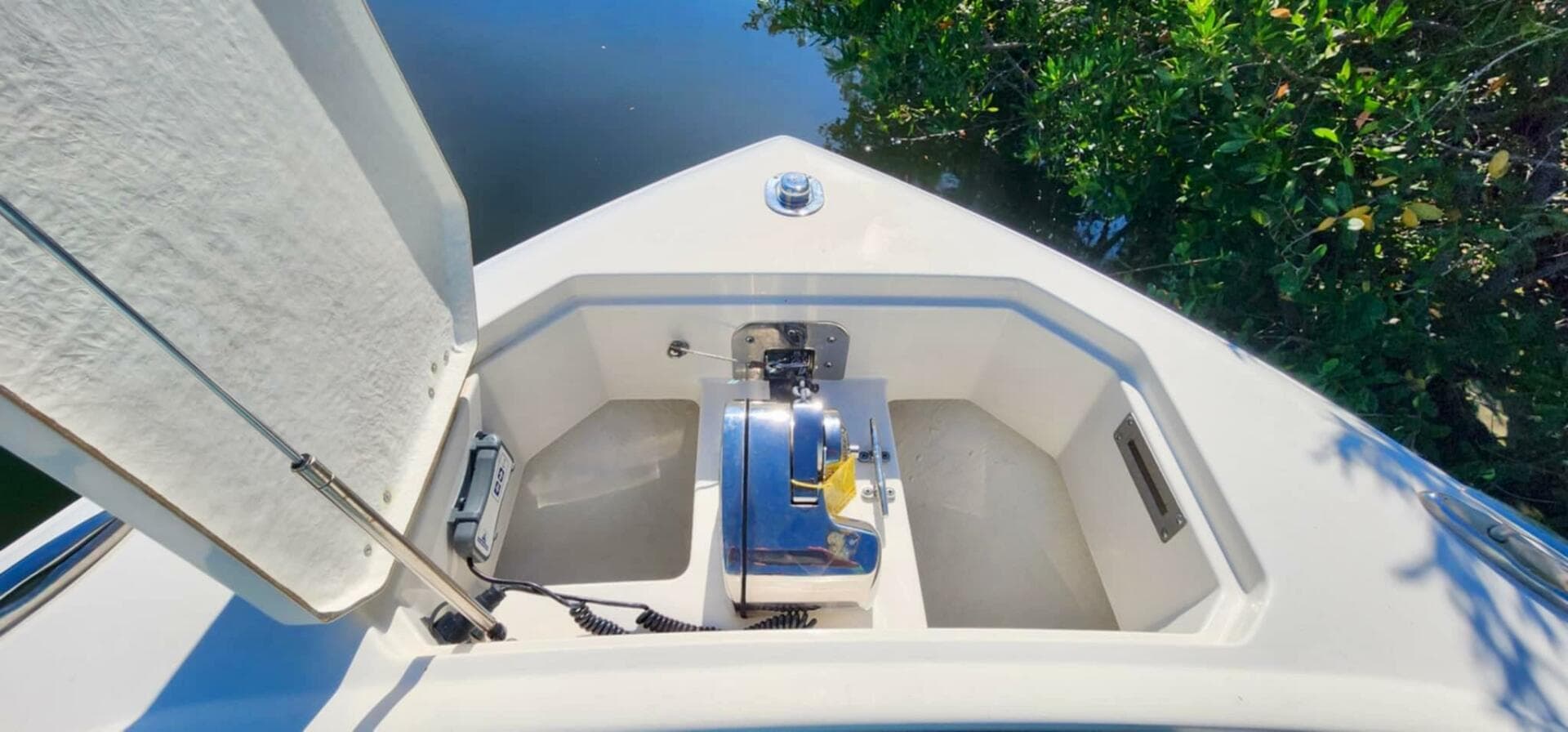 Bow storage compartment on 2021 Sailfish 272 CC boat, open lid, near water and greenery.