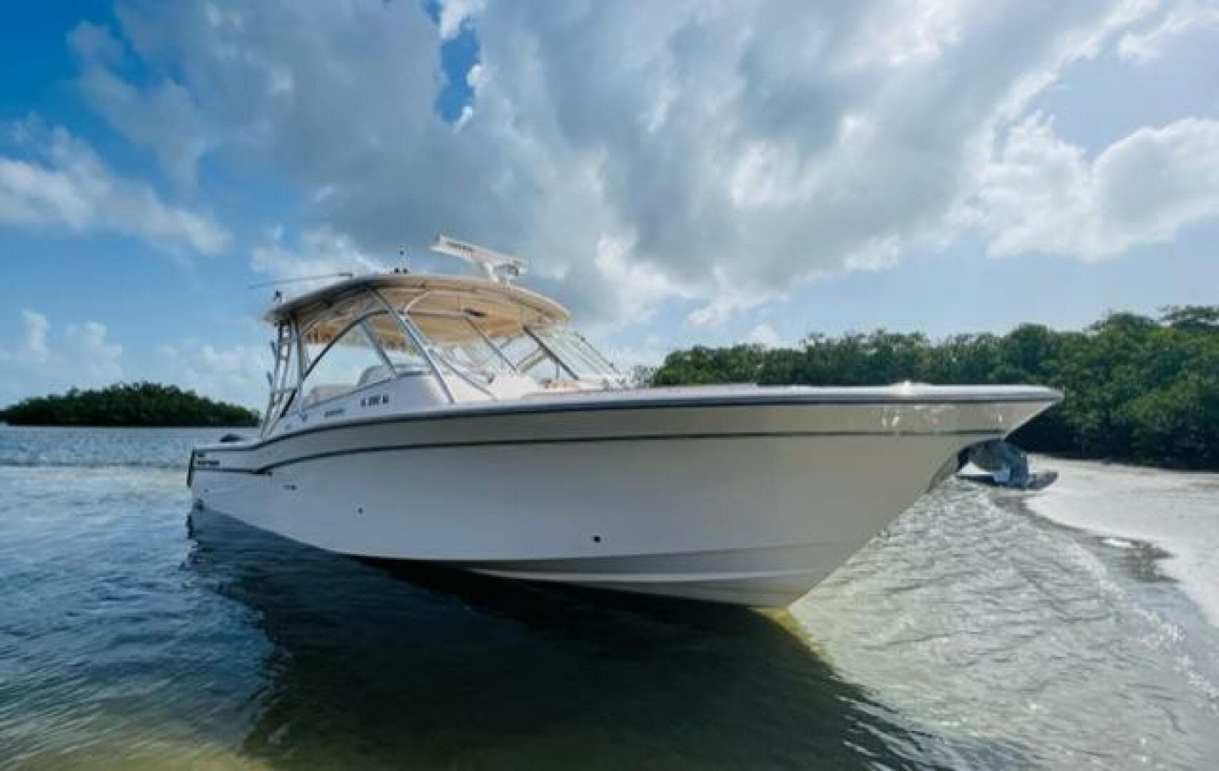 2014 Grady-White Freedom 335 boat anchored near a scenic shoreline under a partly cloudy sky.