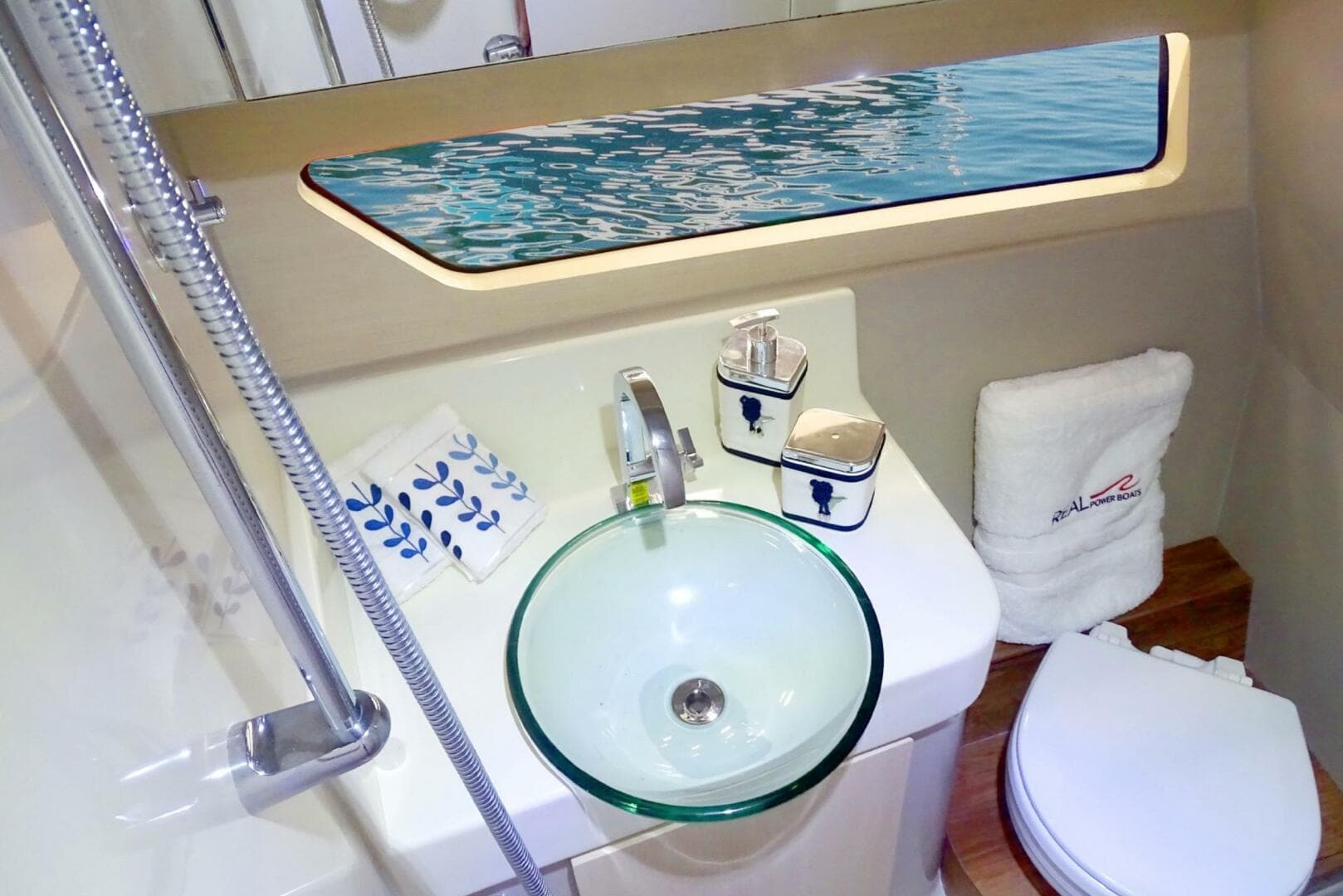 Modern bathroom on 2023 Real 35 Special Deck (SD) boat with glass sink and ocean view.