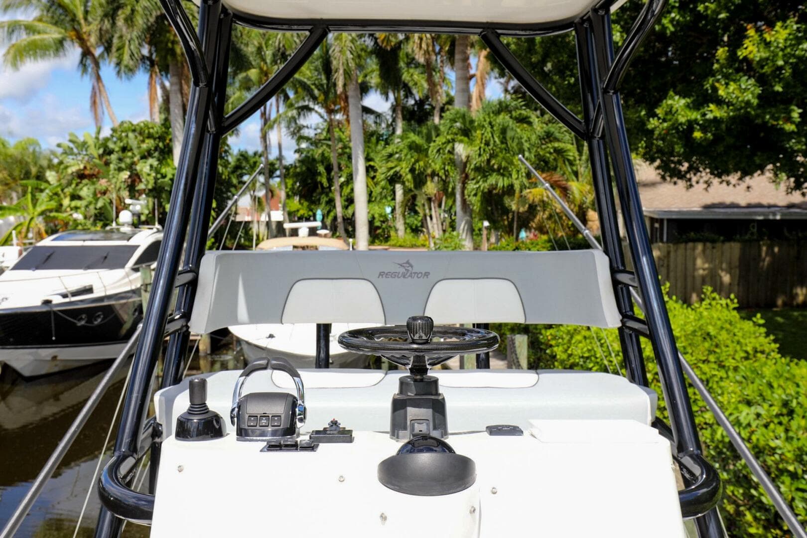 2020 Regulator 41 boat helm with steering wheel and controls, docked near lush greenery.