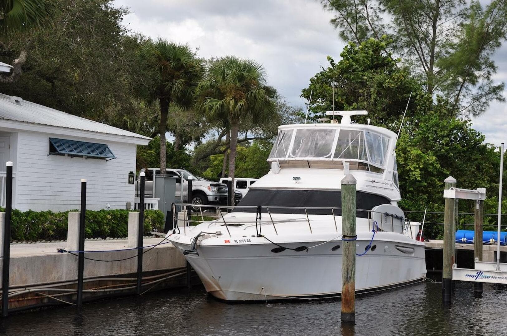 1998 Sea Ray 480 Sedan Bridge yacht docked near a white house.