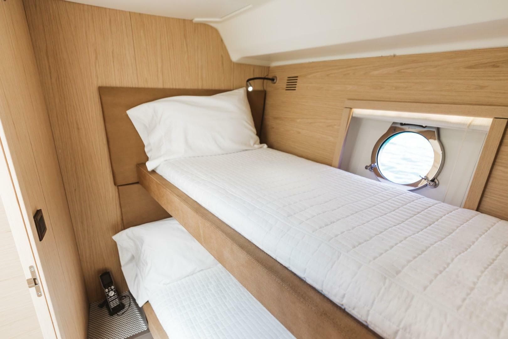 Cozy twin cabin in 2015 Beneteau Monte Carlo 5 yacht with porthole view.