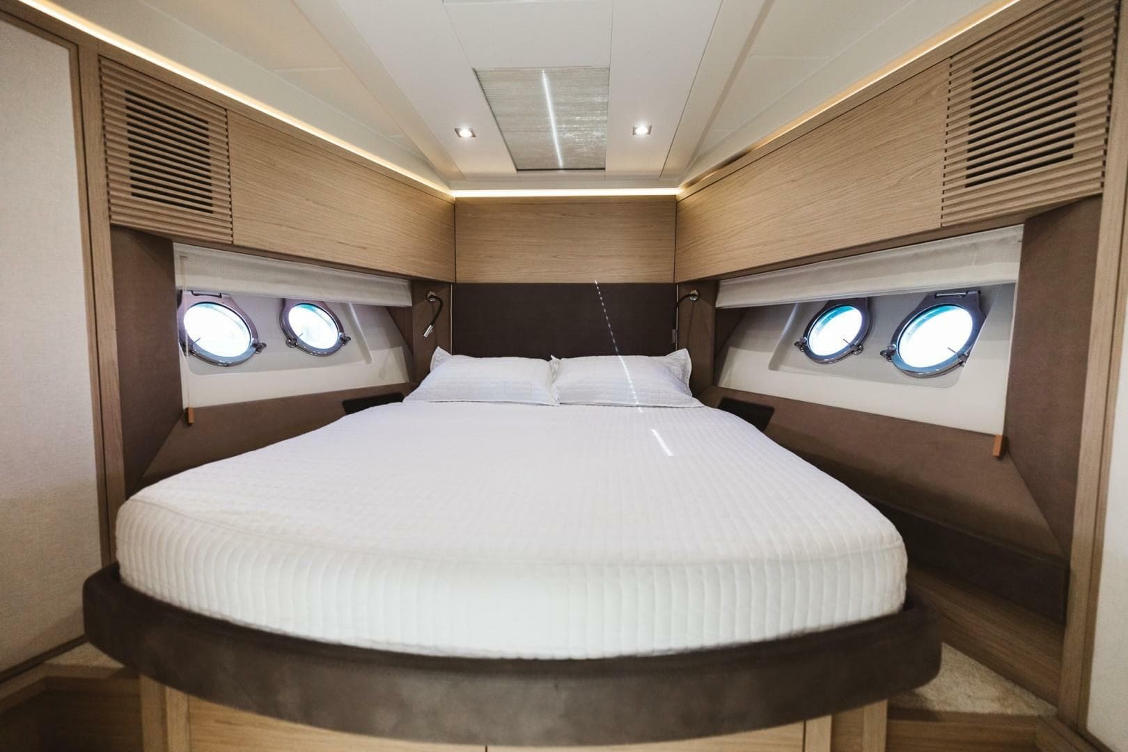 Luxurious bedroom interior of 2015 Beneteau Monte Carlo 5 yacht with round windows.