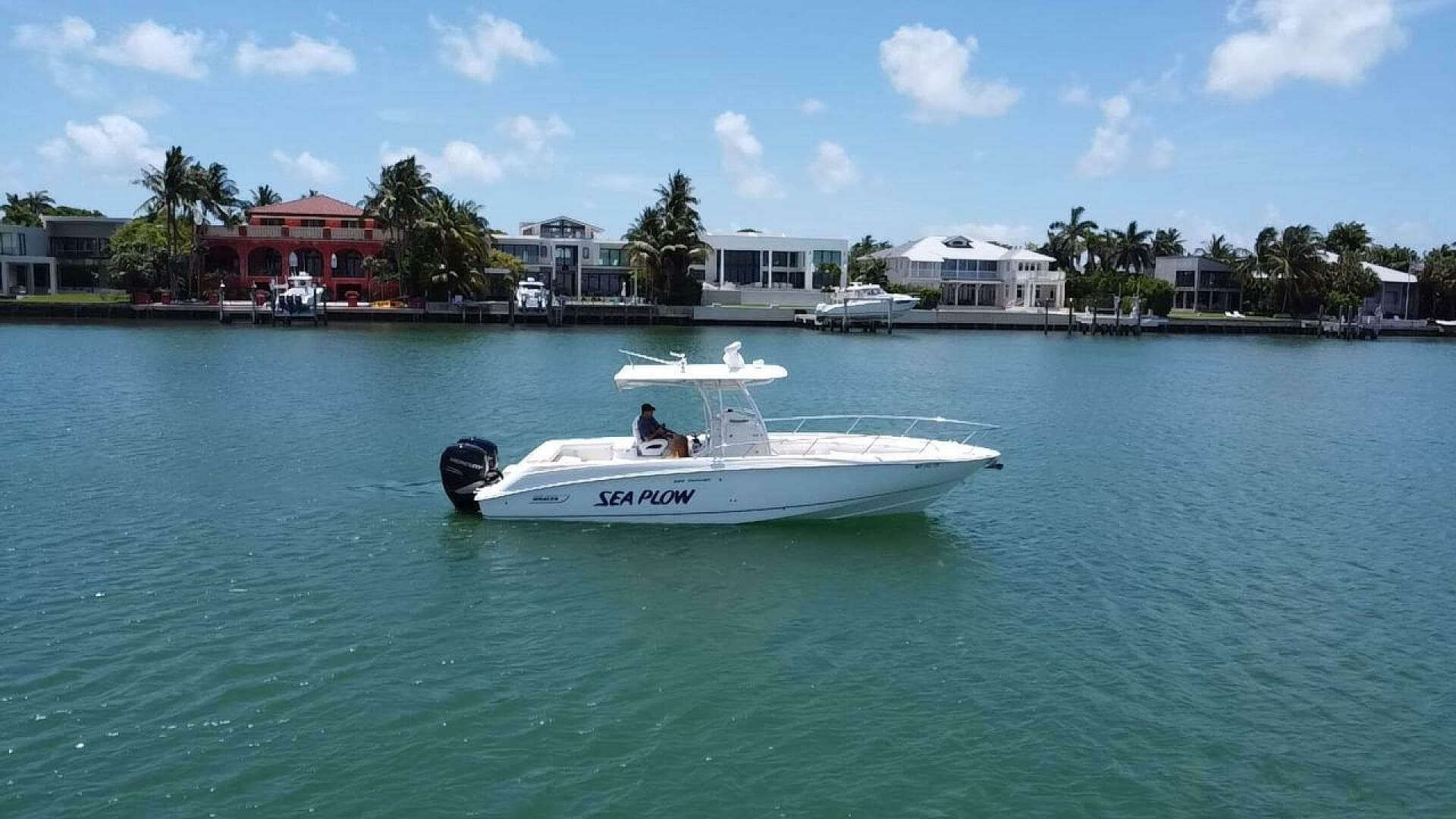 2008 Boston Whaler 320 Outrage boat named Sea Plow on calm water near waterfront homes.