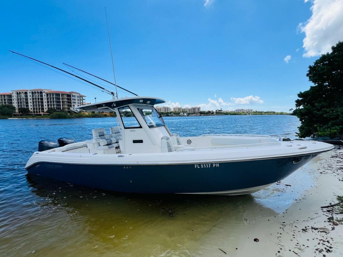 2012 Everglades 295 Center Console boat on sandy shore, blue sky background.