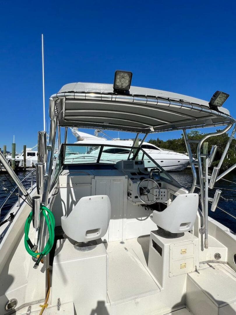 1988 Grady-White 25 SAILFISH boat with dual seats and canopy, docked under clear blue sky.