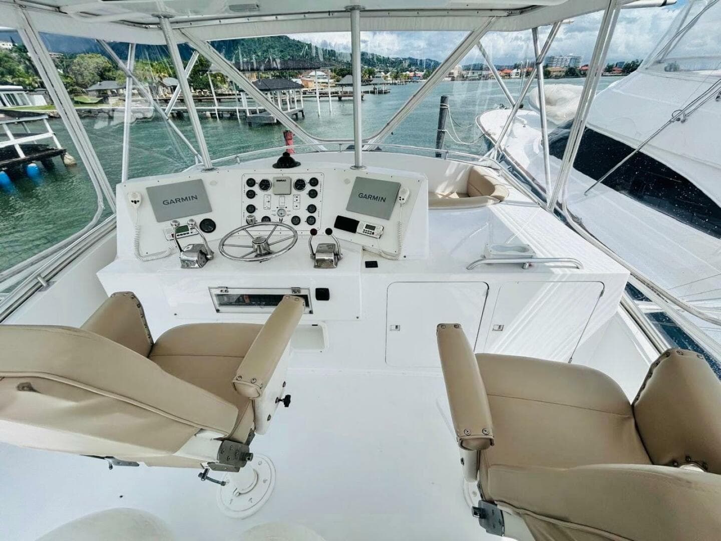 1988 Bertram 54' yacht helm with dual Garmin displays and beige captain chairs.