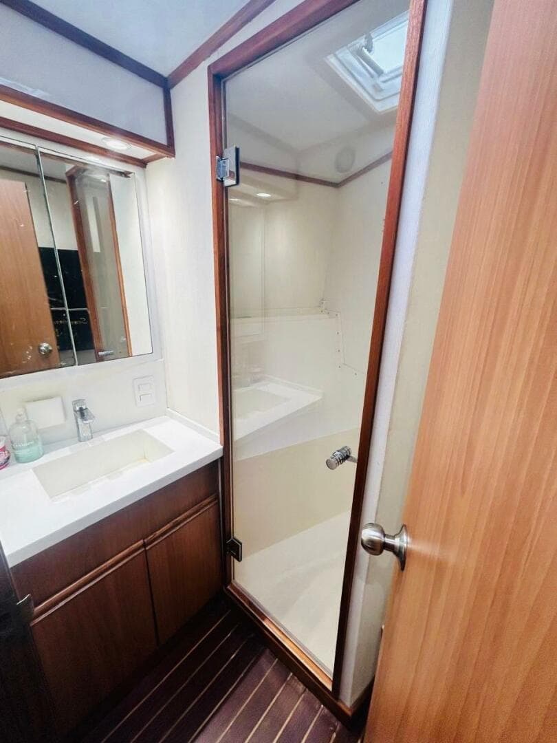 1988 Bertram 54' yacht bathroom with glass shower and wooden cabinetry.