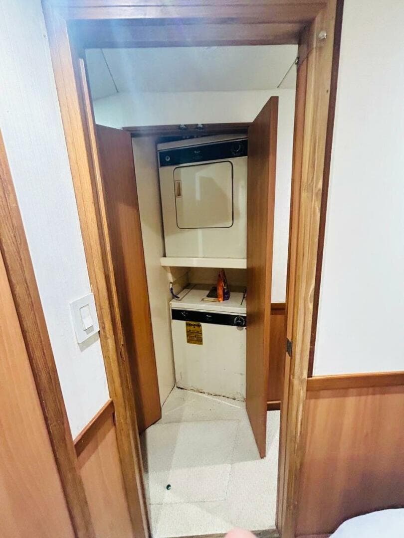 Laundry area inside 1988 Bertram 54' yacht with wood paneling and compact washer-dryer.