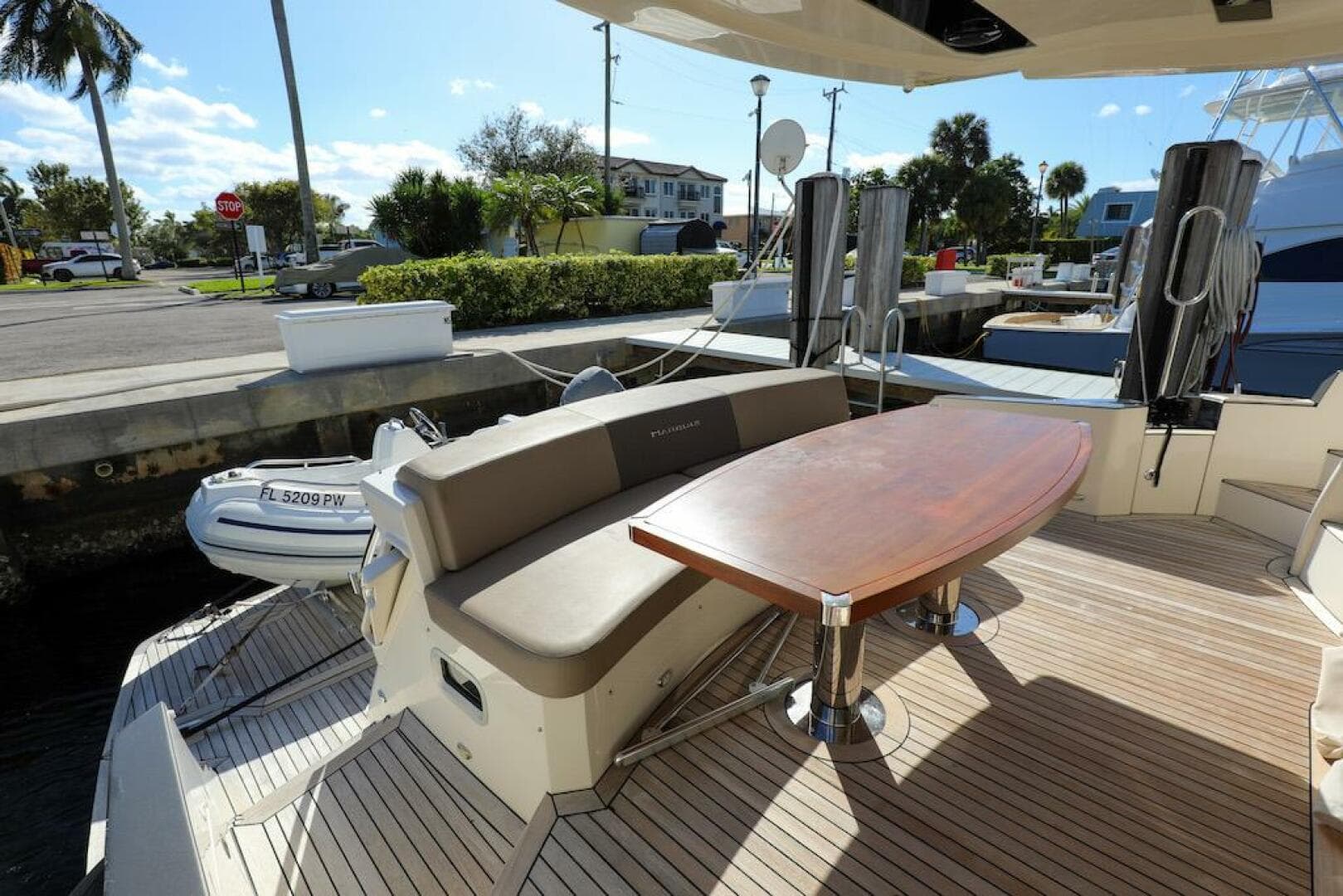 2016 Marquis 660 Sport Yacht deck with seating and table, docked in a sunny marina.