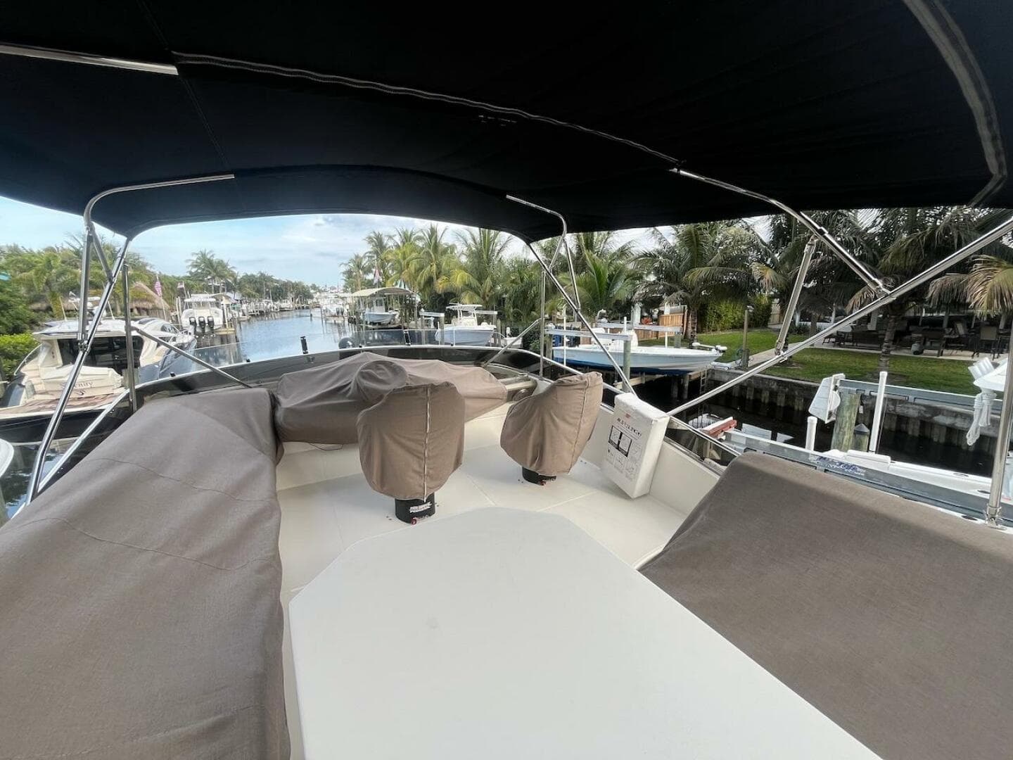 2017 Marquis 500 Sport Yacht deck with covered seating, docked in a scenic marina.