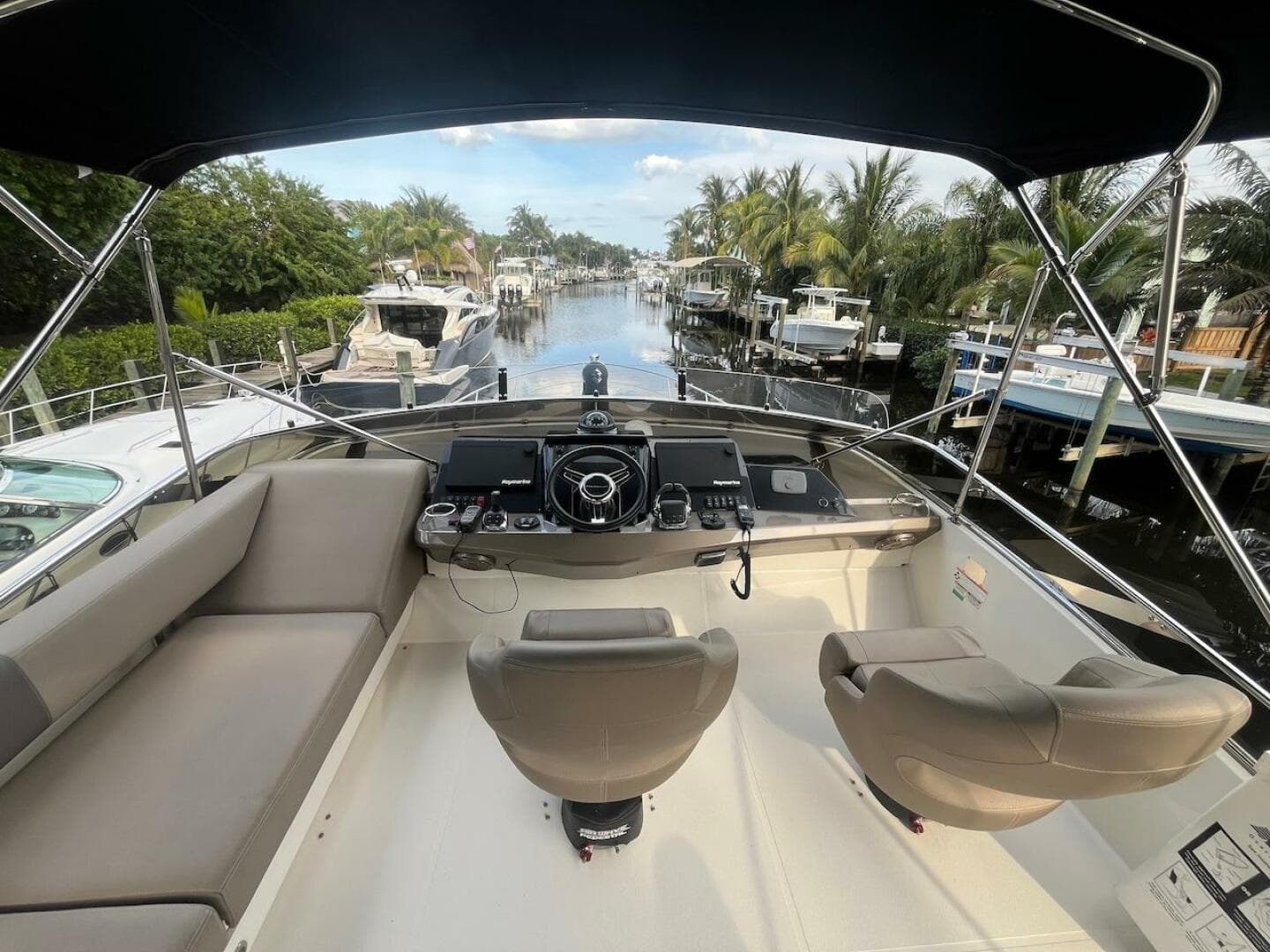 2017 Marquis 500 Sport Yacht helm with dual seats, docked in a scenic marina.