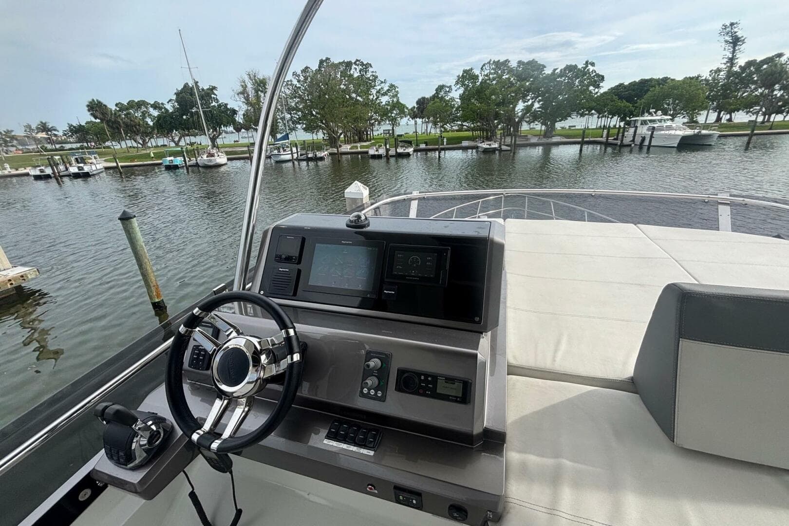 Galeon 500 Fly 2020 yacht helm with steering wheel and control panel, docked in a marina.
