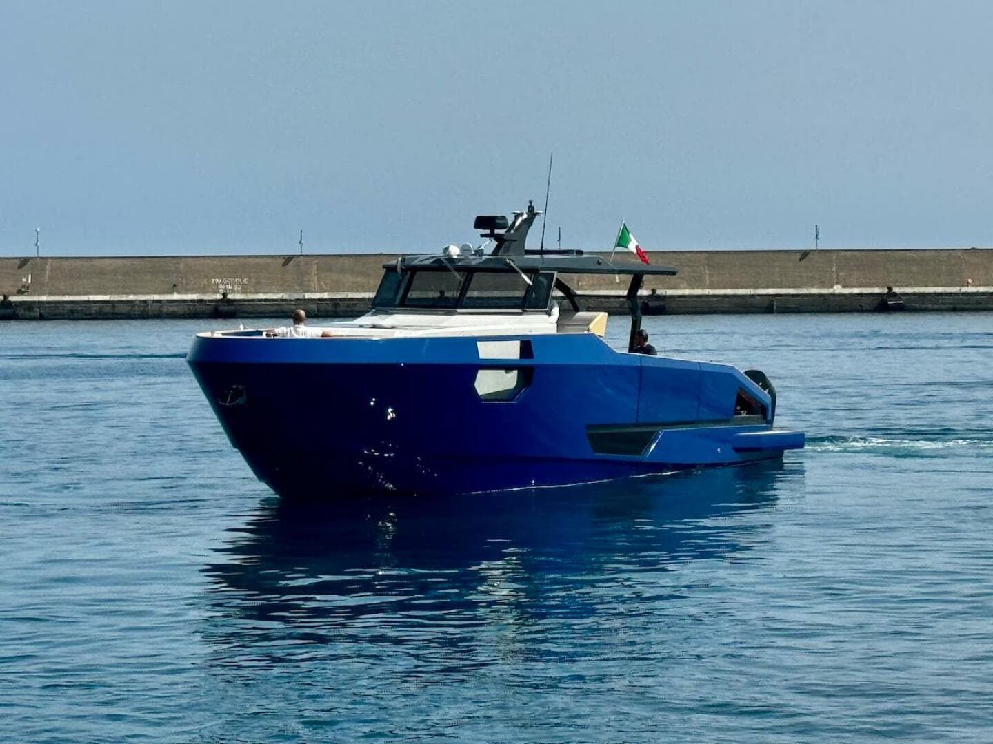 Aicon Audace 50 yacht, 2025 model, cruising in calm waters near a concrete pier.