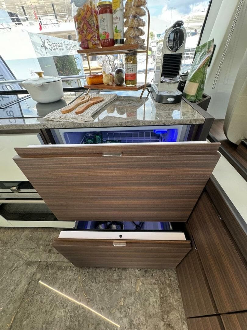 Luxury yacht kitchen with modern appliances, featuring wood cabinetry and marble countertops on Aicon 66 Vivere 2024.