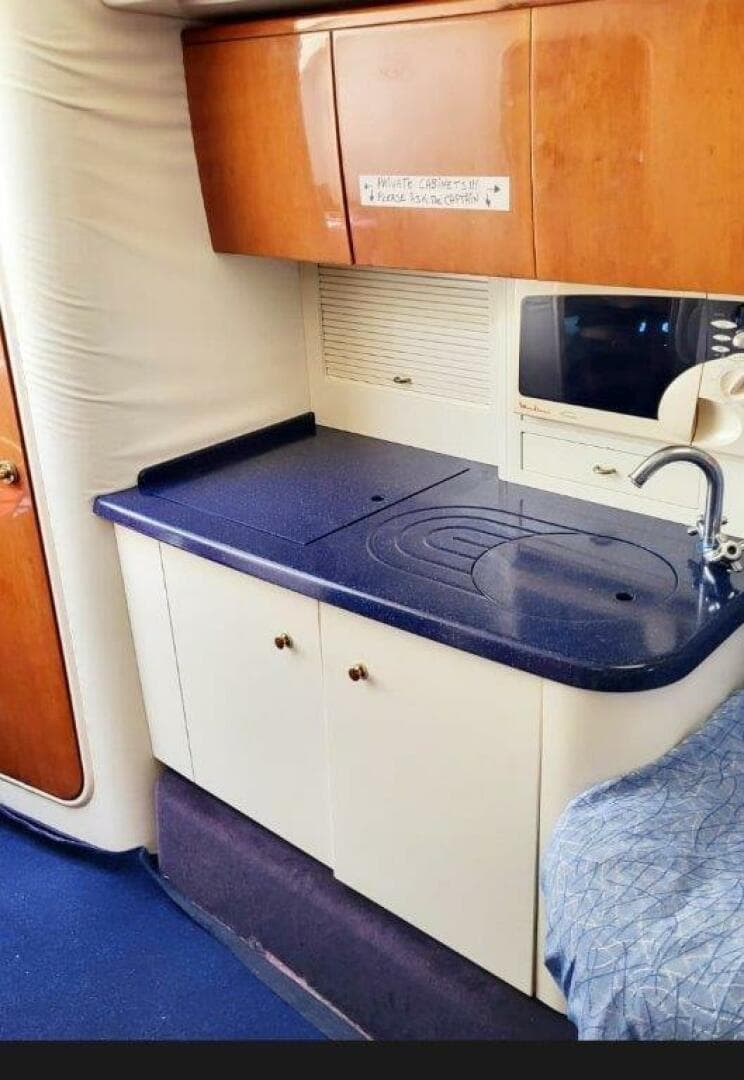 2003 Cranchi Endurance 39 yacht interior kitchen with wooden cabinets and blue countertop.