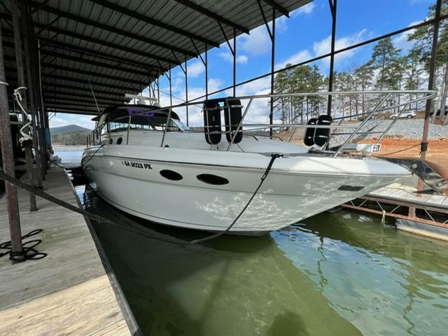 2003 Sea Ray 380 Sundancer docked under a covered marina with scenic background.