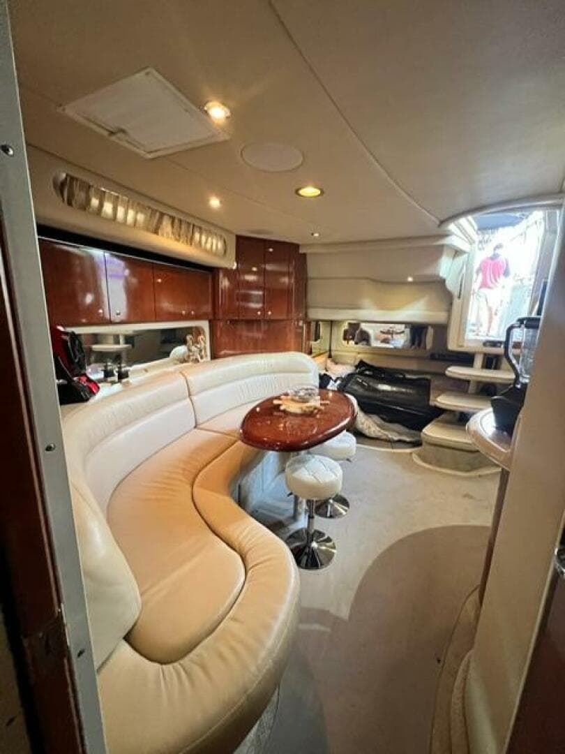 2003 Sea Ray 380 Sundancer interior with curved seating and wooden table.