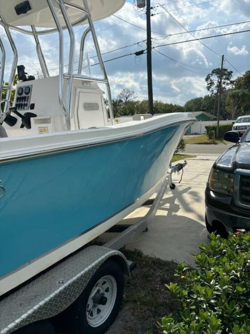 2016 Release 208 RX boat on trailer, parked beside a black vehicle, under a partly cloudy sky.