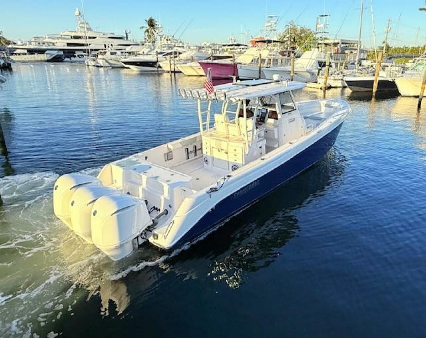 2014 Everglades 355 Center Console boat docked in marina, featuring triple outboard engines.