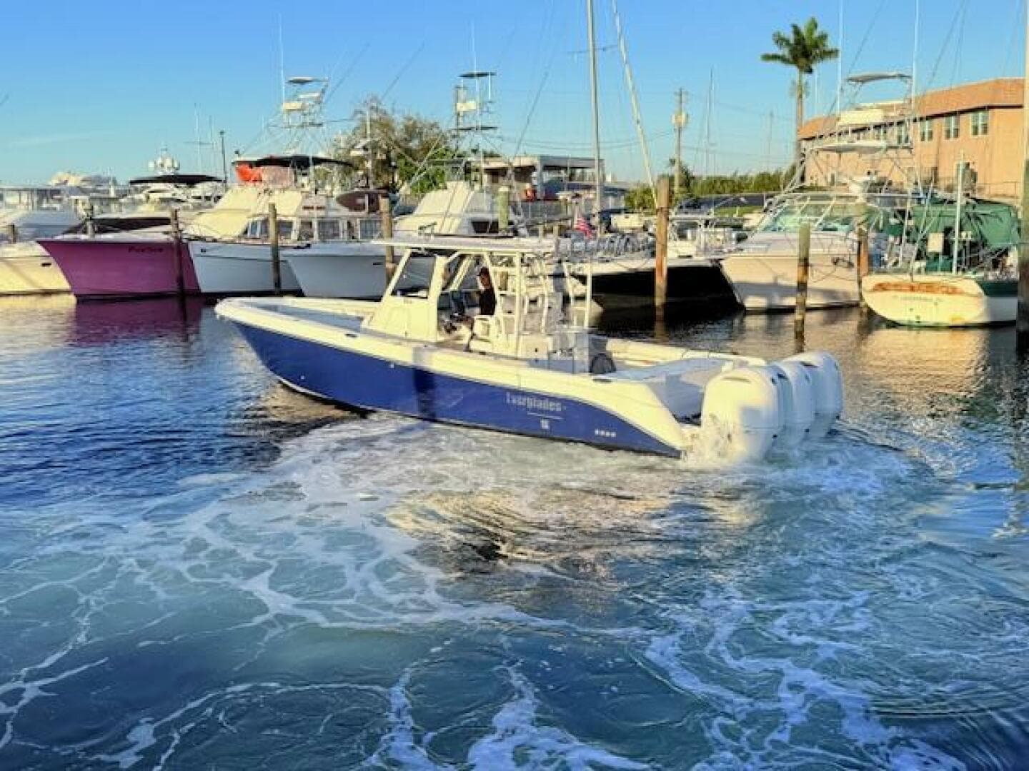 2014 Everglades 355 Center Console boat in marina, surrounded by other vessels.