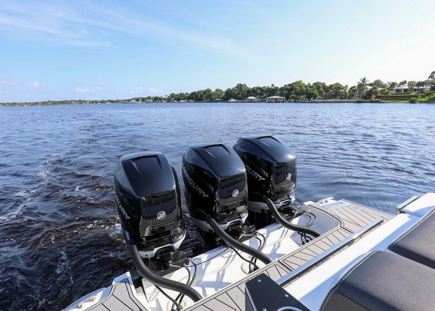 2023 Monterey 385 Super Sport boat with triple outboard engines on a calm lake.