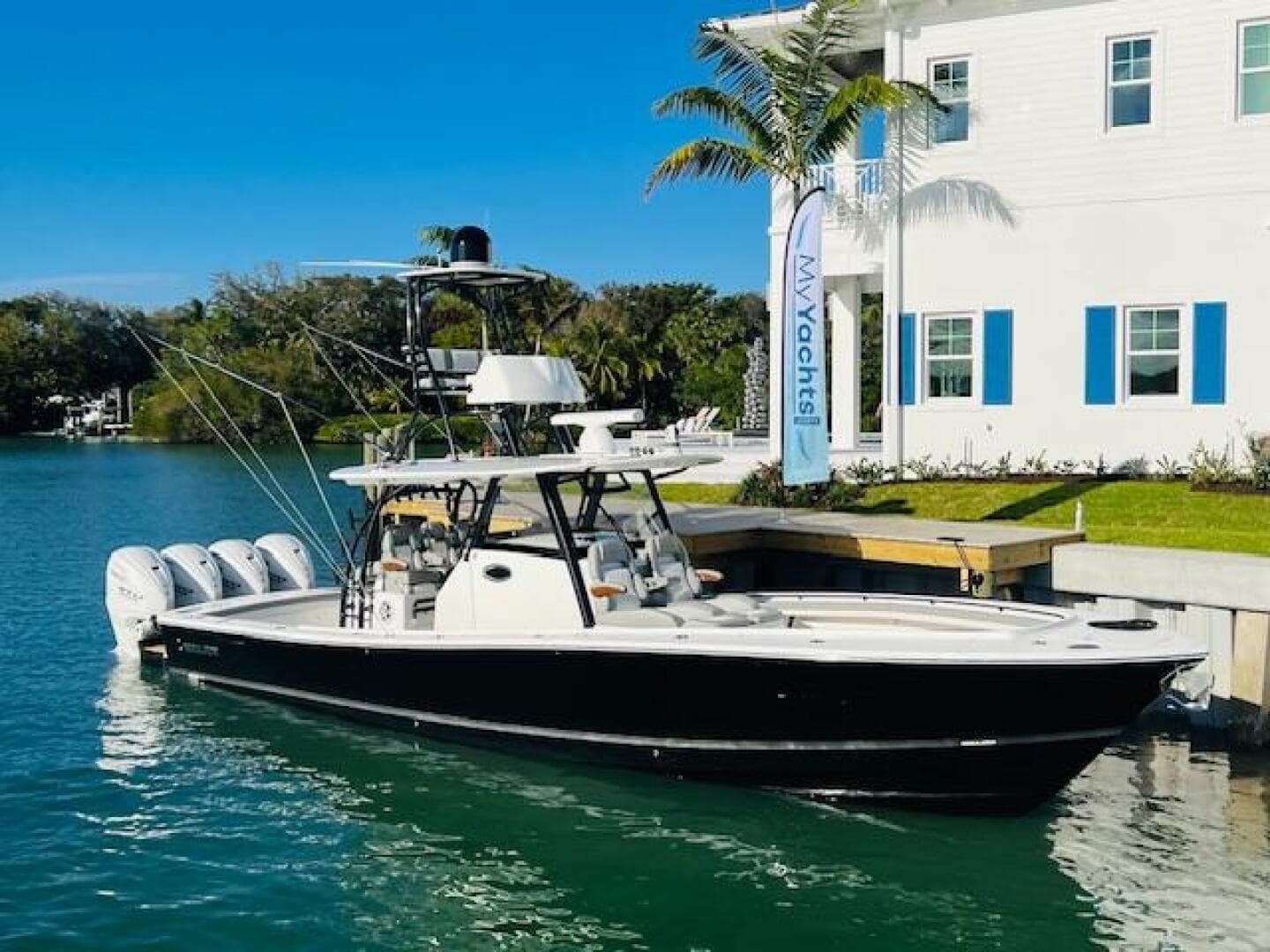2024 Regulator 41 boat docked by a waterfront house with palm trees.