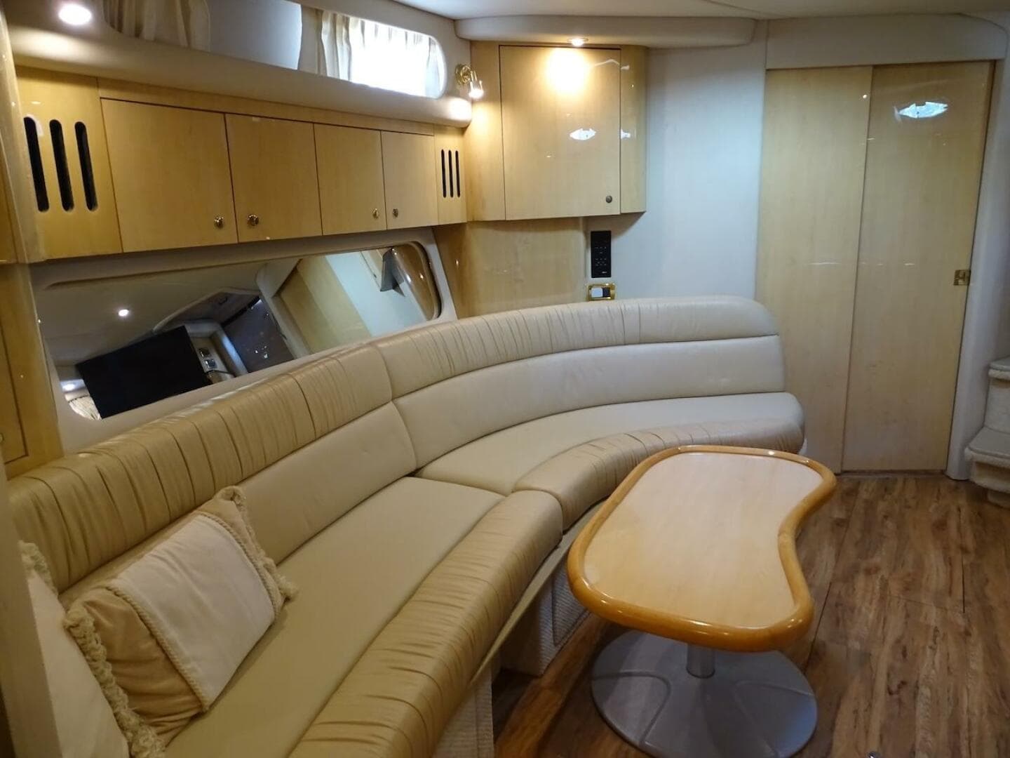 Luxurious interior of 2001 Sea Ray 410 Sundancer yacht with curved seating and wooden table.