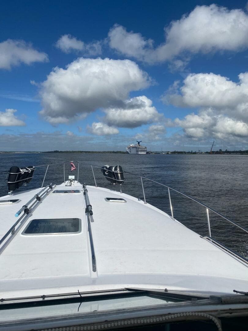 1993 Sea Ray 440 Sundancer cruising on a sunny day with scattered clouds.