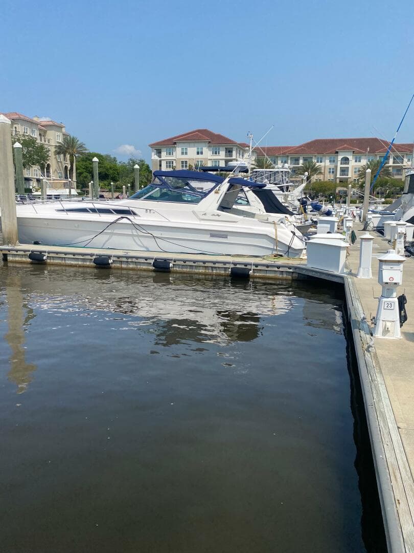 1993 Sea Ray 440 Sundancer docked at a marina with waterfront buildings in the background.