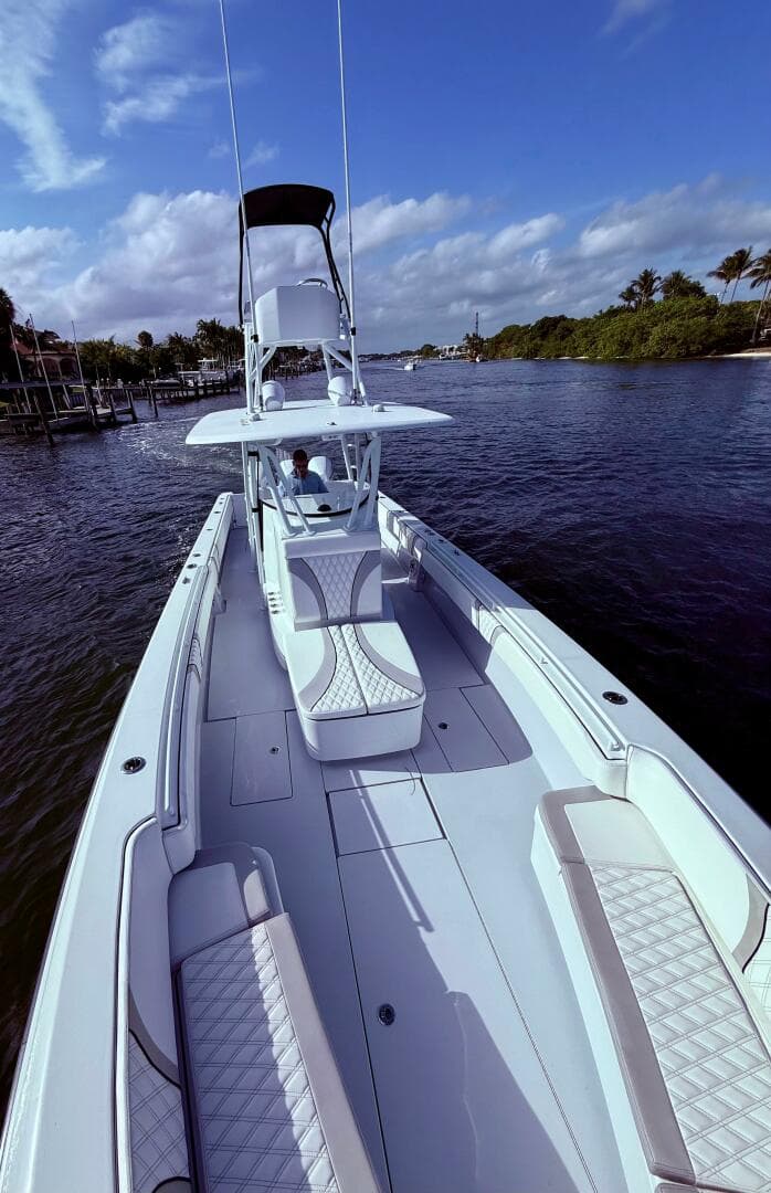 2024 Contender 39 ST boat cruising on a scenic waterway under a clear blue sky.