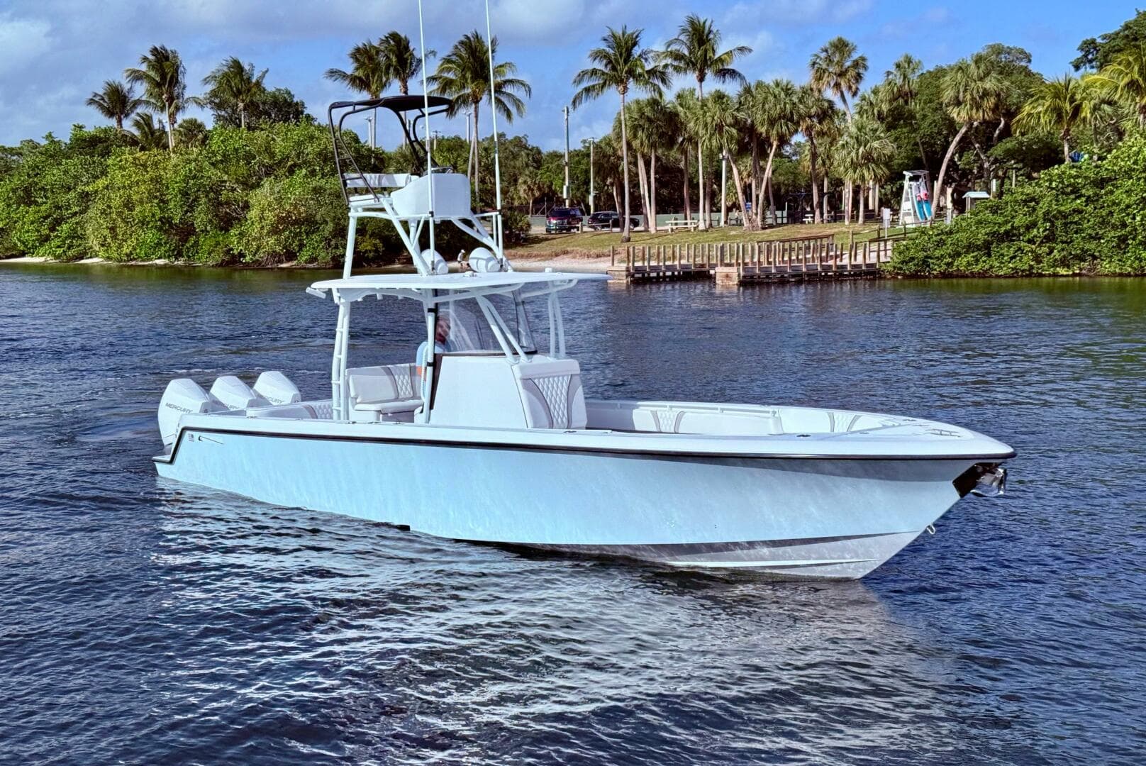 2024 Contender 39 ST boat cruising on a scenic waterway with palm trees in the background.
