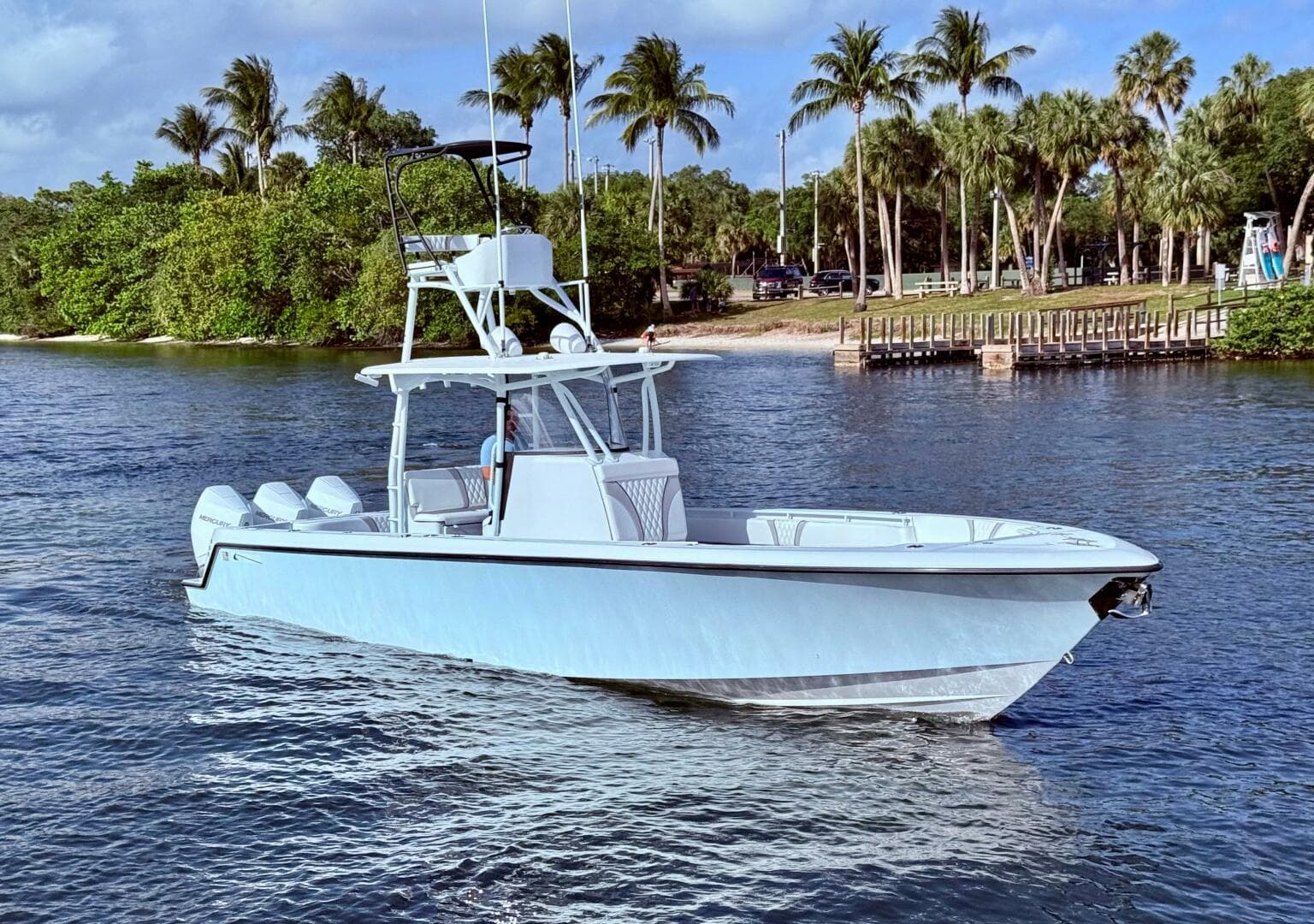 2024 Contender 39 ST boat on water, surrounded by palm trees and a dock.